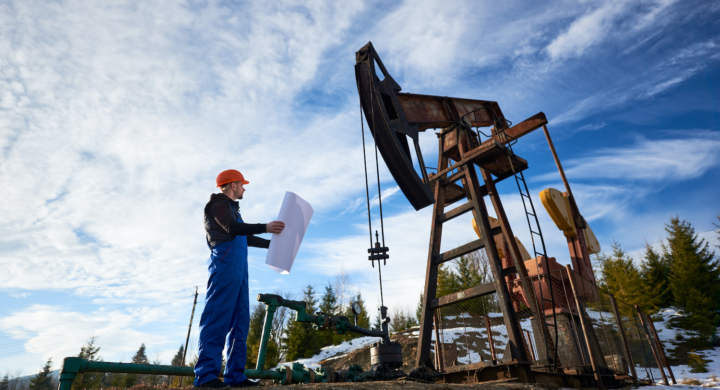 oil-worker-standing-in-the-oilfield-next-to-a-pump-jack-with-a-big-paper
