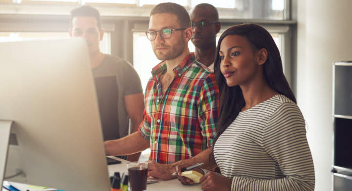four-diverse-workers-standing-next-to-computer