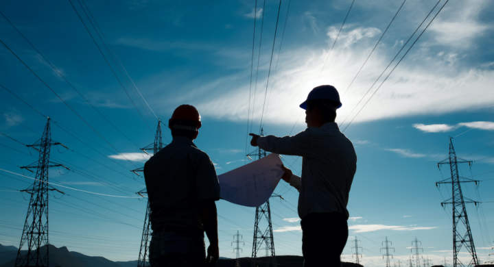 silhouette of two engineers standing at electricity station, discussing plan