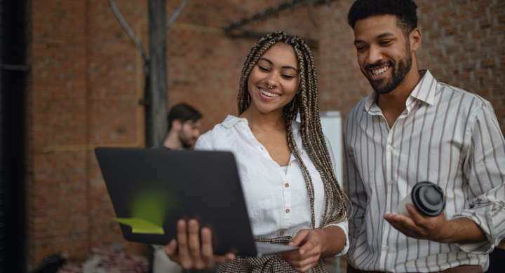Cheerful young businesspeople with tablet working in office, a cooperation concept.