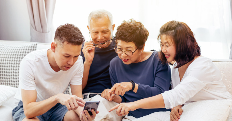Asian family of all ages looking at a smartphone in their living room