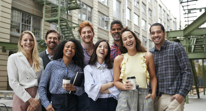 friendly-coworkers-laugh-to-camera-outside-their-workplace