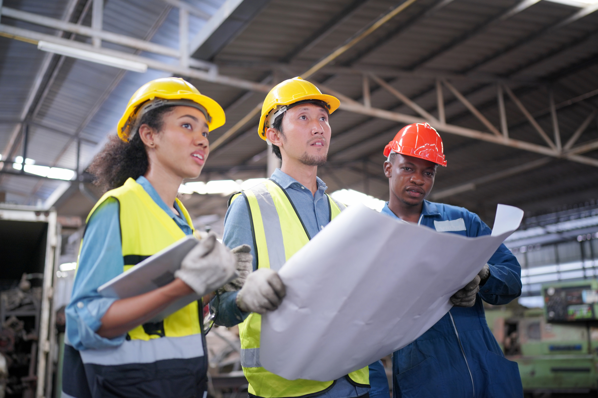 Three Heavy Industry Entrepreneurs and Engineers Stand in Pipe Manufacturing Factory, Use Digital Tablet Computer, Have Discussion. Design and Construction