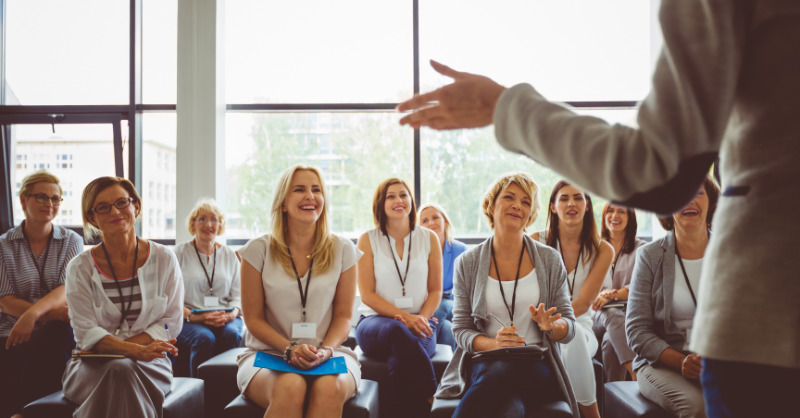 a speaker addressing a crowd of women in a corporate setting