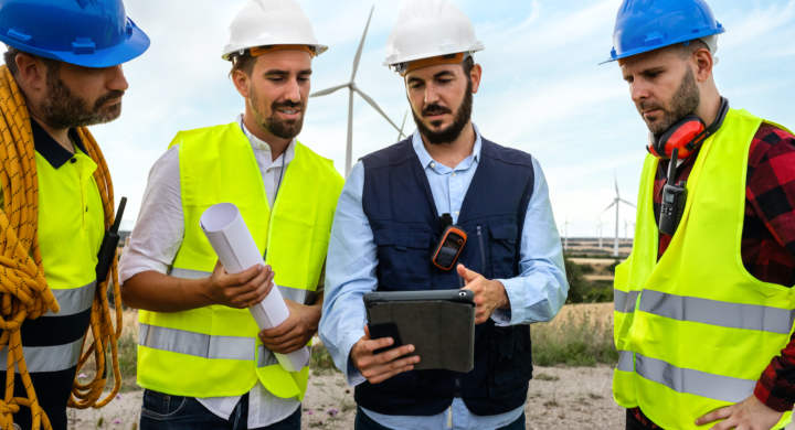 electric-engineer-explaining-maintenance-workers-plans-for-wind-turbine-farm-renewable-energy