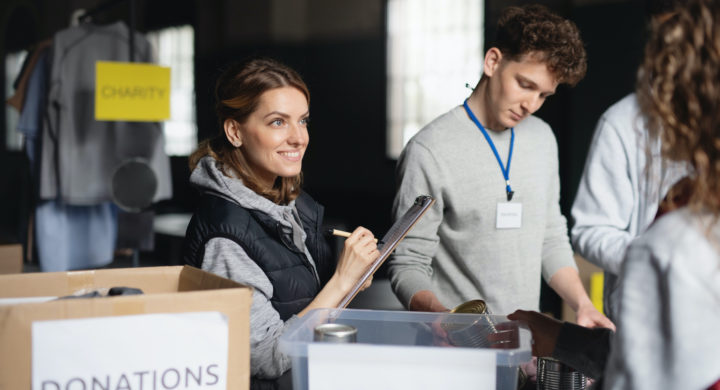 A group of volunteers working in community charity donation center, sorting out clothes and canned food.
