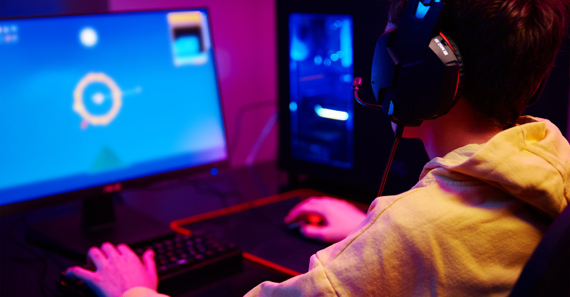 a person in a yellow hoodie is playing a video game on a computer