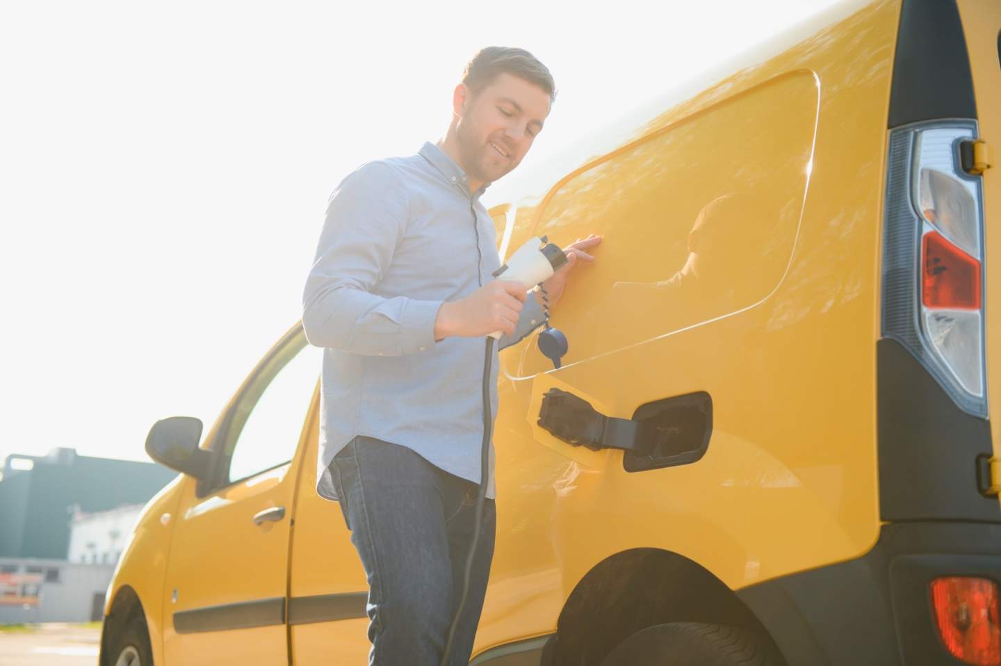 Man Charging Electric Vehicle With Cable.