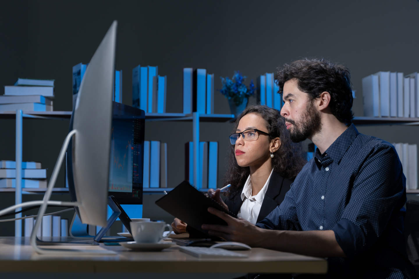 business men and women who are working hard Working late into the night to complete tasks according to set goals The two of them looked at the company's financial graph attentively.