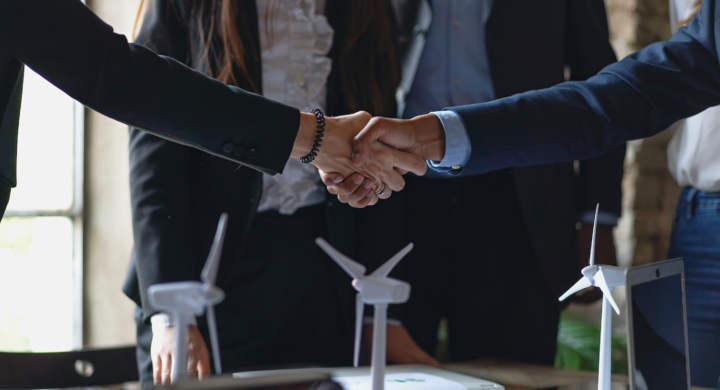 Handshake between two business partners, surrounded by wind turbine models and charts. Ideal for illustrating themes of partnership, renewable energy, and sustainability - business lifestyle