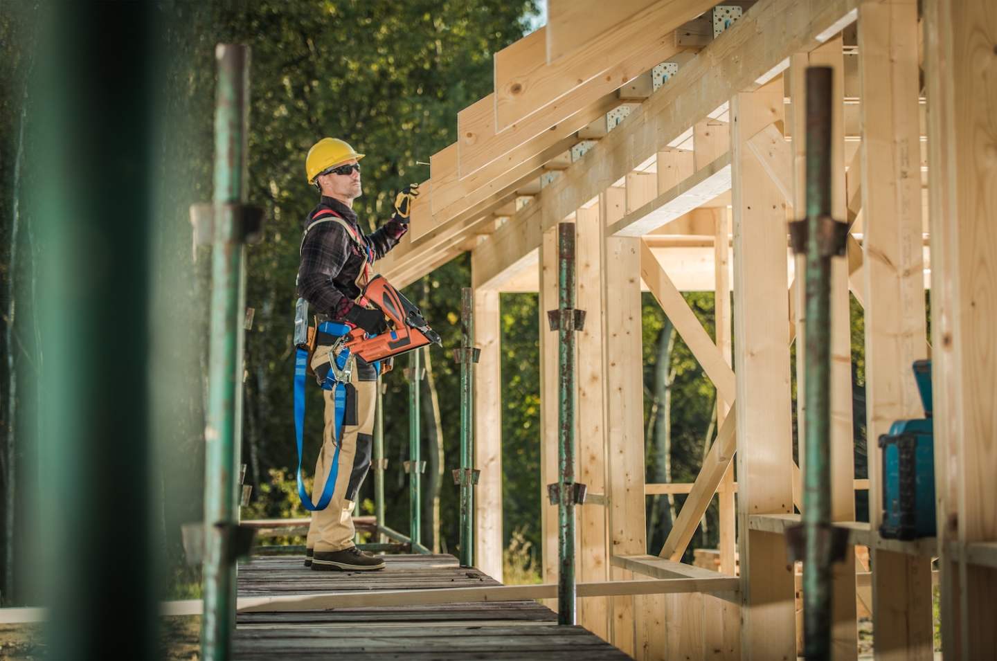 Caucasian Construction Contractor in His 30s with Nail Gun. Wood House Frame Building. Industrial Theme.