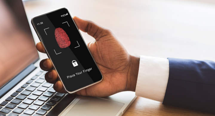 Biometric Identification Concept. African American Man Holding Cellphone In Hand, Showing Application For Fingerprint Scanning With A Zone To Touch With Thumbprint Icon On The Device Screen