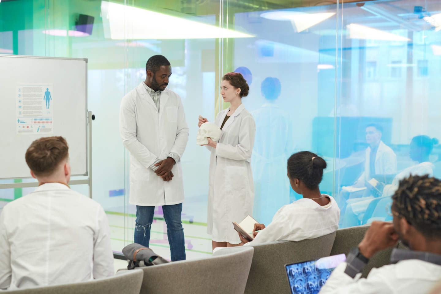 Portrait of young woman standing by whiteboard while giving presentation during medical seminar in college, copy space