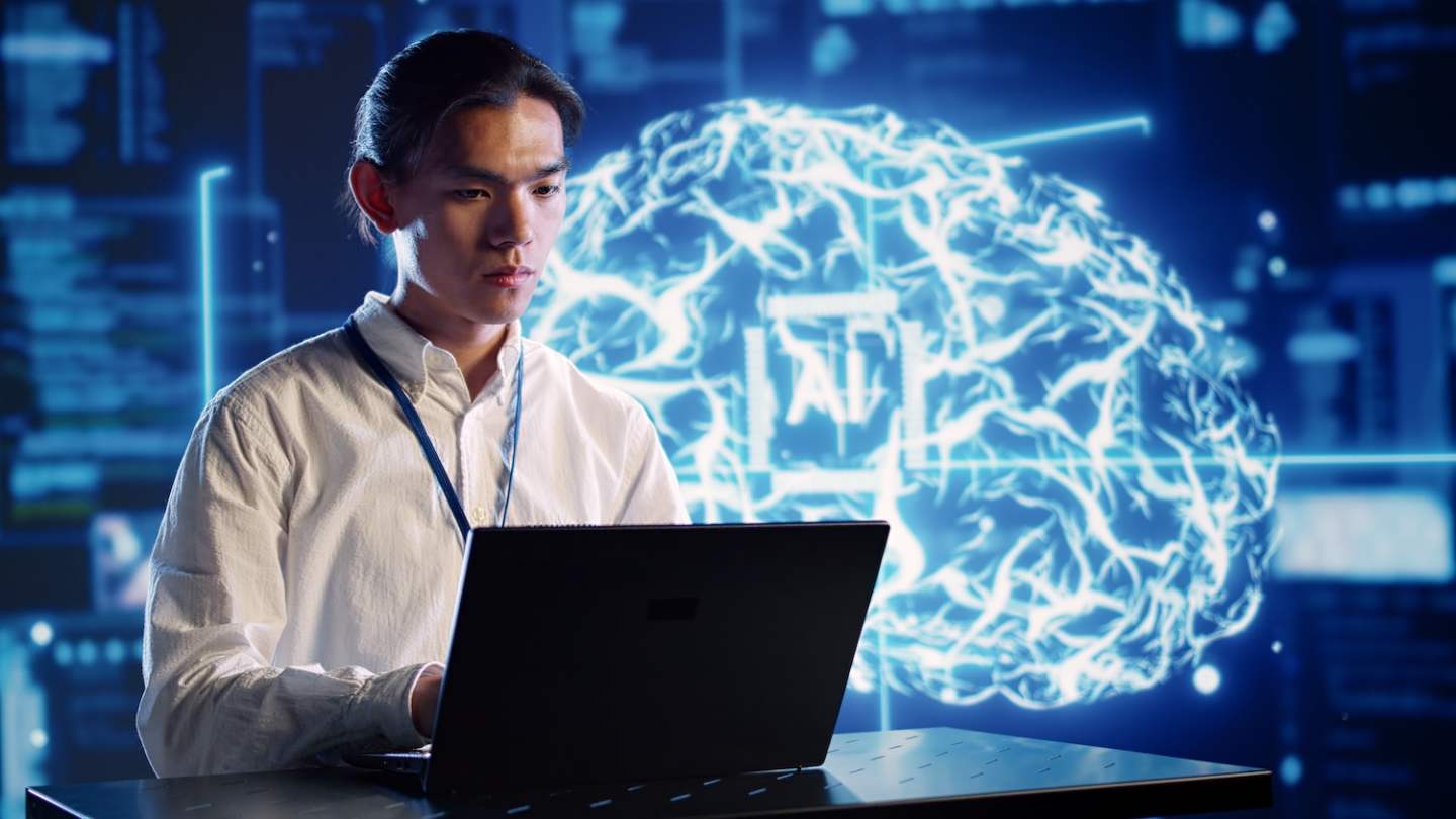 Organized engineer in high tech facility uses artificial intelligence computing simulating human brain. Dilligent admin doing operations on laptop with AI machine learning algorithms