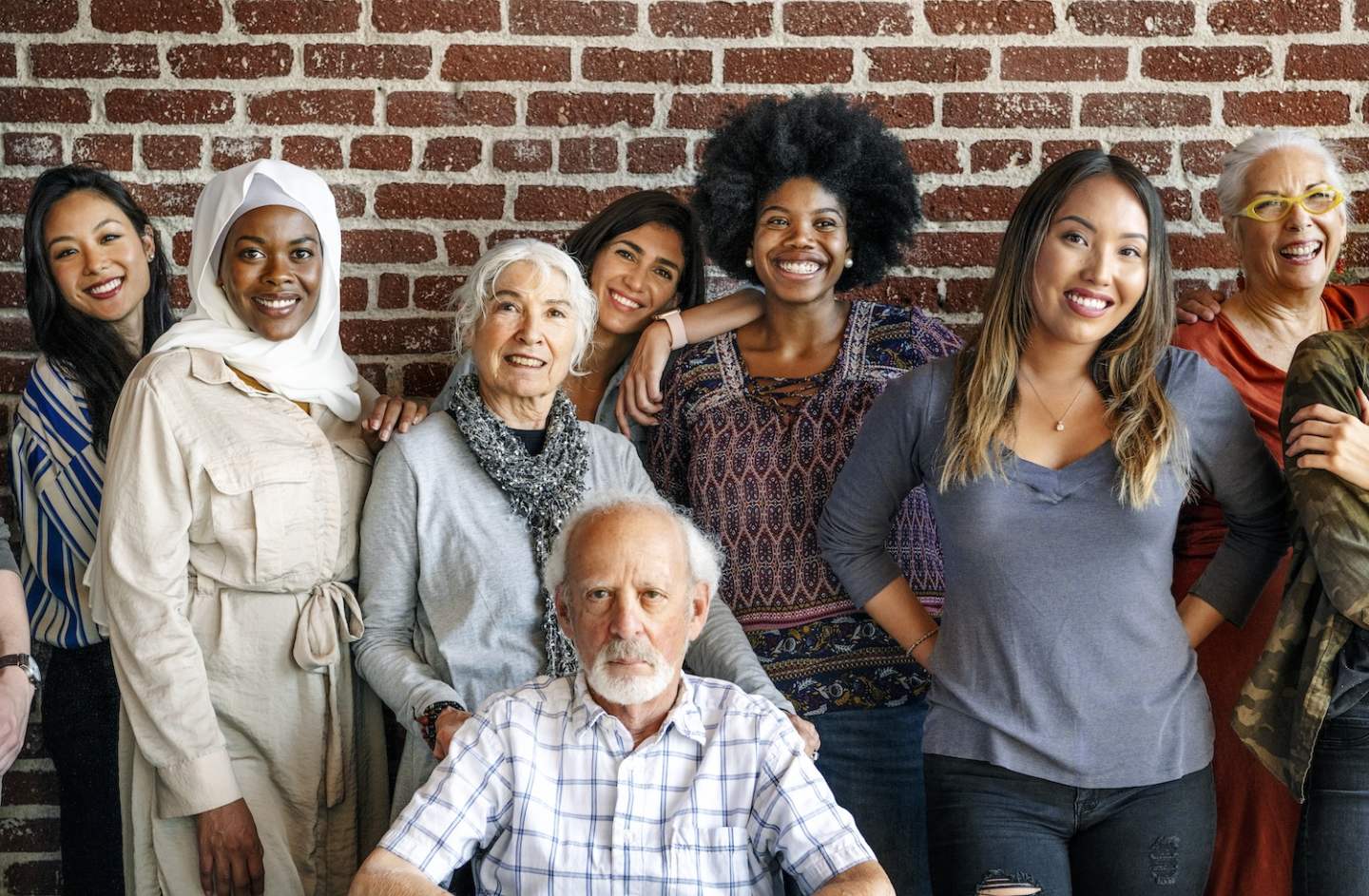 Group of diverse people standing in front of a brick wall