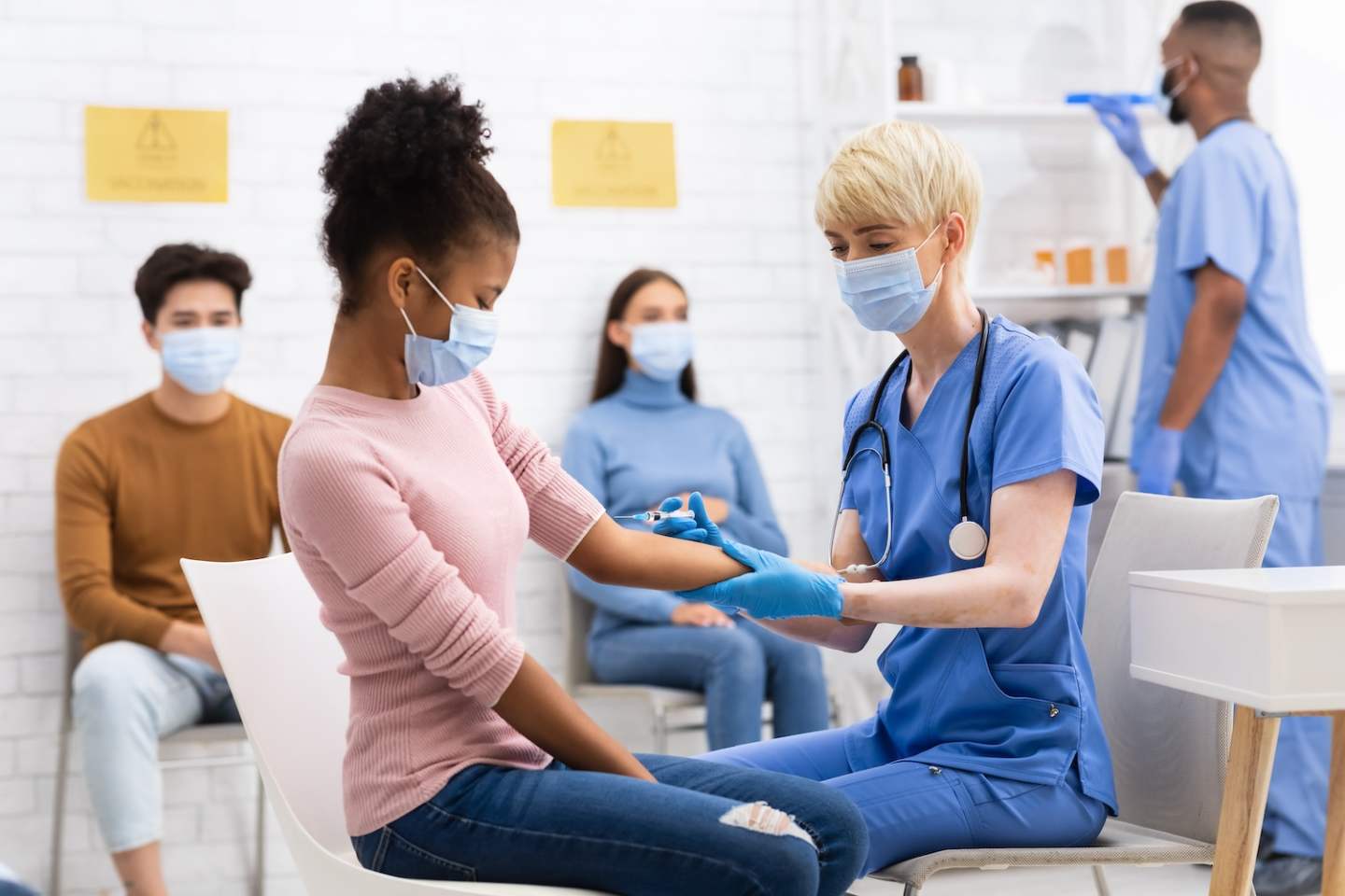 Covid-19 Vaccination. African American Teen Girl Receiving Coronavirus Vaccine Injection Shot In Arm Sitting With Doctor In Hospital. Corona Virus Medicine Treatment And Prevention. Selective Focus