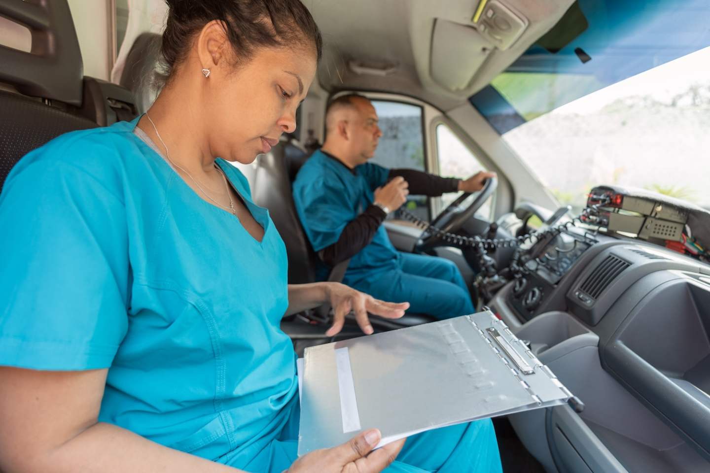 Close up photo of an hispanic woman reading medical informs inside an ambulance while her partner driving