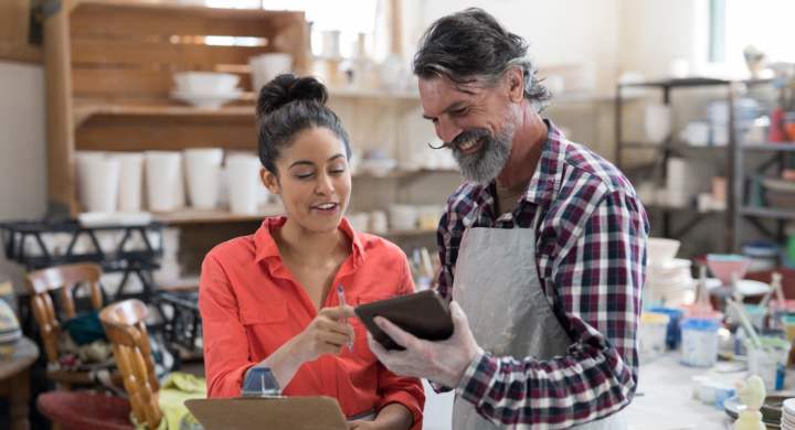 Male and female potter discussing over tablet pc in the pottery workshop