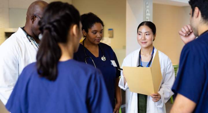 smiling-asian-female-doctor-with-folder-talking-with-diverse-colleagues-in-hospital-corridor-hospital-medical-and-healthcare-services