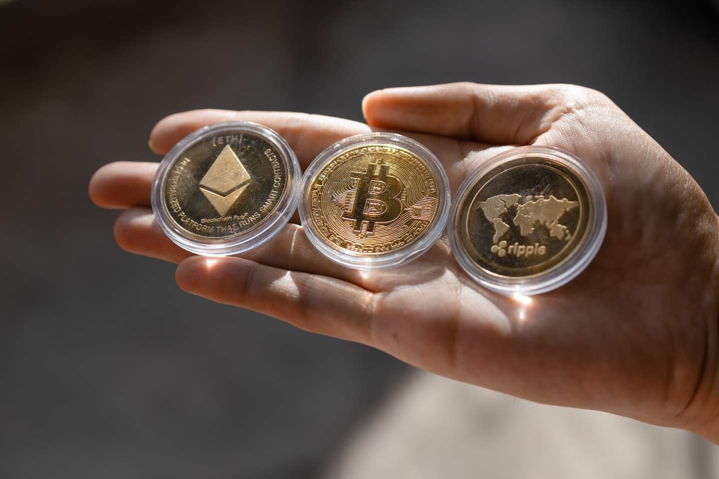 Young man holding Crypto tokens Bitcoin, Ethereum, Ripple on palm of hand - Cryptocurrency and Digital asset concept