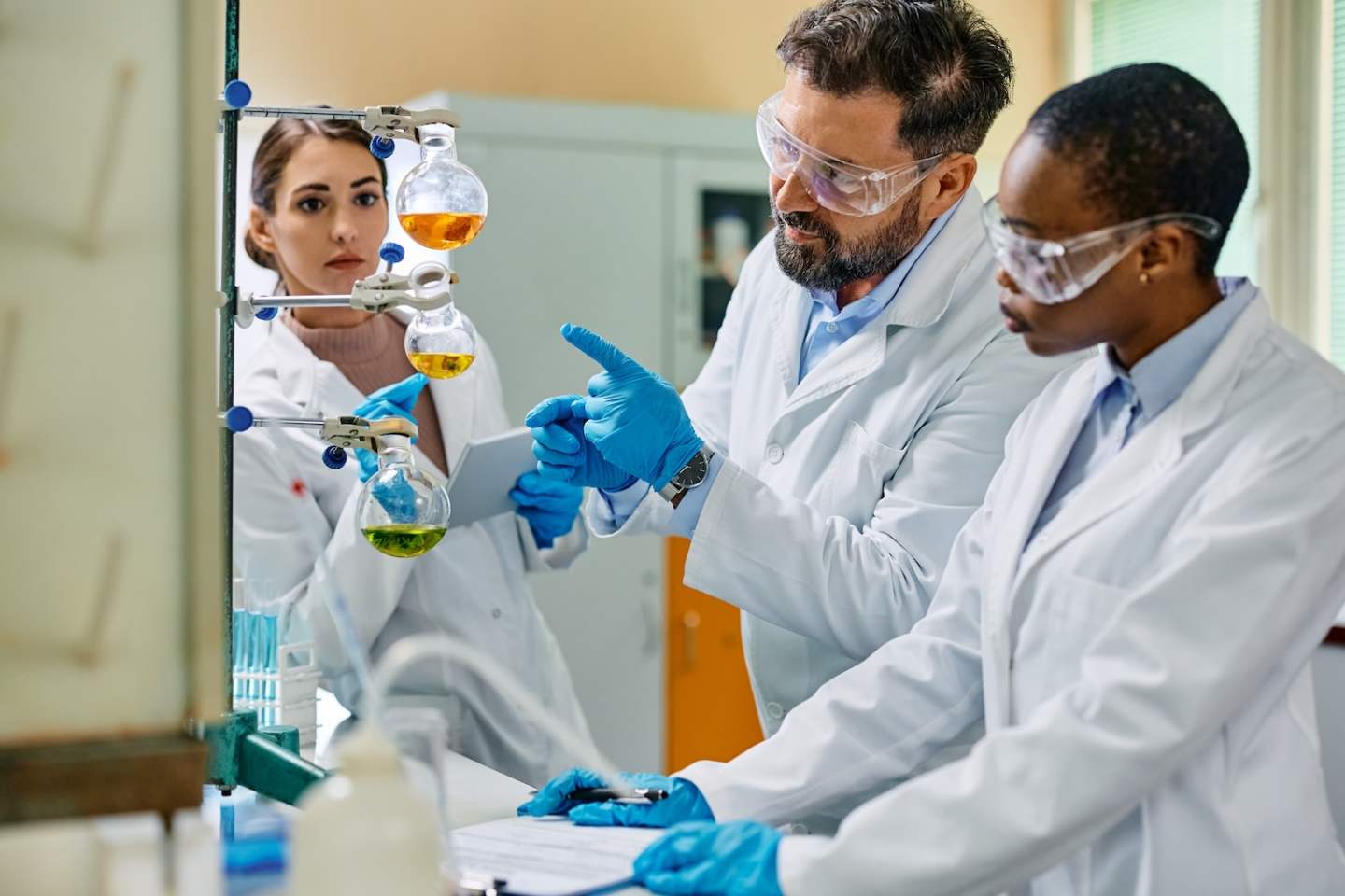 Pharmaceutical scientist and his female colleagues cooperating while working in laboratory.