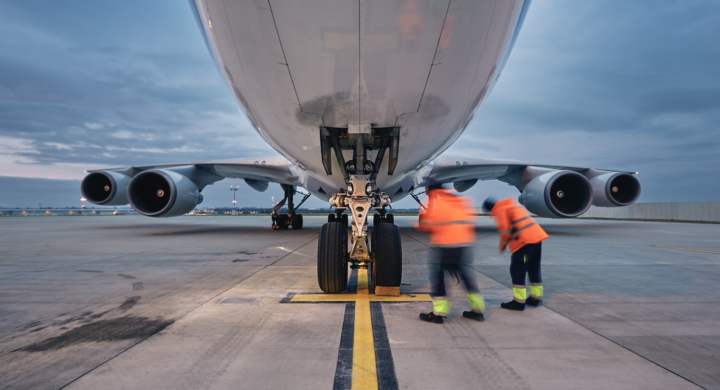 Low angle view of freight airplane. Ground staff at airport. Preparation cargo plane before flight during sunny day.