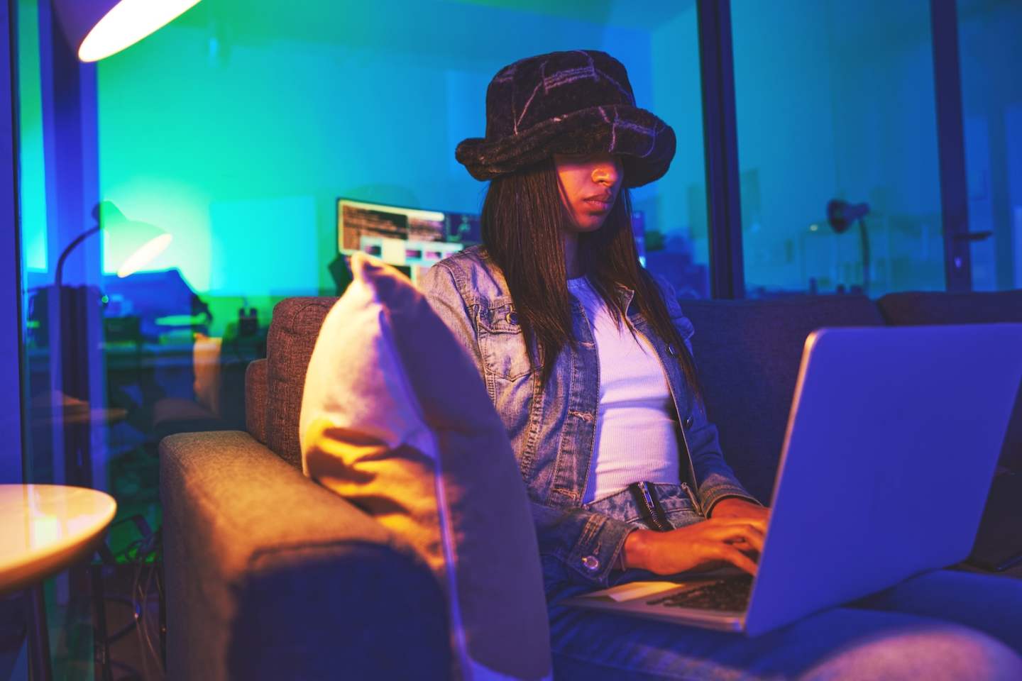 Programmer, hacker and woman typing on laptop in home at night in neon light to hack software. Cybe.