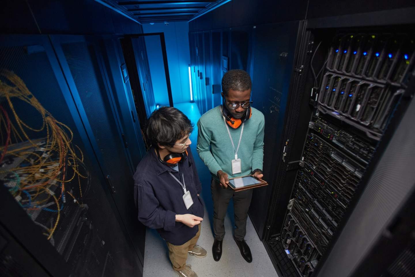 High angle view at two young technicians setting up server network while working in data center, copy space