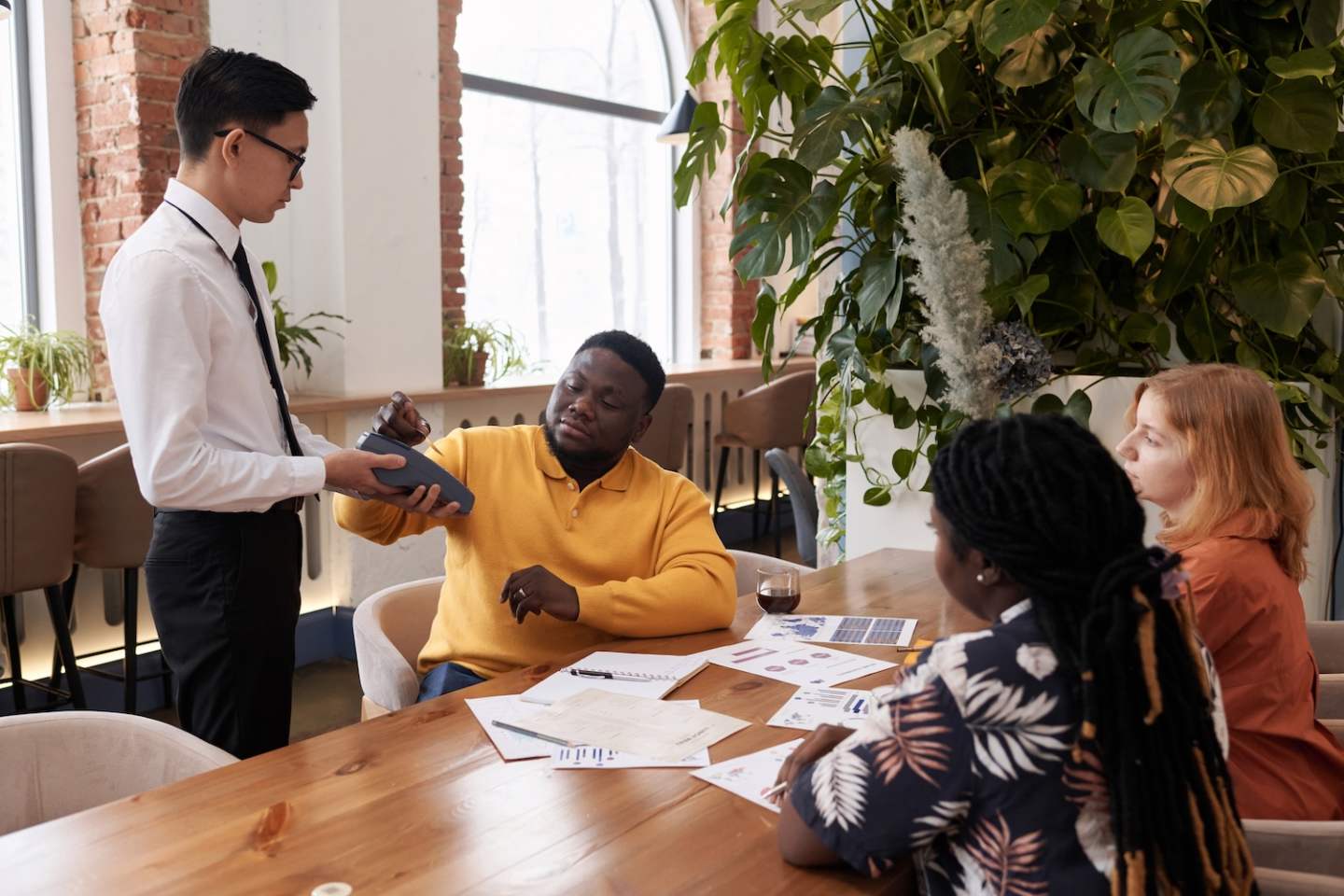 Young African American businessman paying for lunch in modern restaurant with credit card during meeting in cafe, copy space