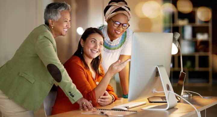 Creative, collaboration and business women on computer at night in office for teamwork, planning or.