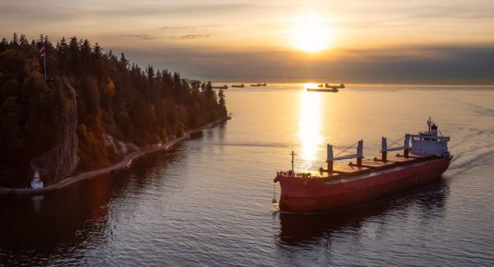 Vancouver, British Columbia, Canada. Aerial View from Above of a Cargo Ship arriving to the Port near Stanley Park during a vibrant sunny sunset.