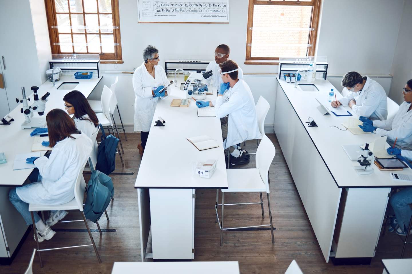 Education, science and students in lab classroom with professor and equipment for test. Technology,.