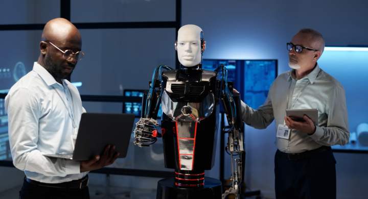 Engineers using gadgets to connect robot during their teamwork in the laboratory