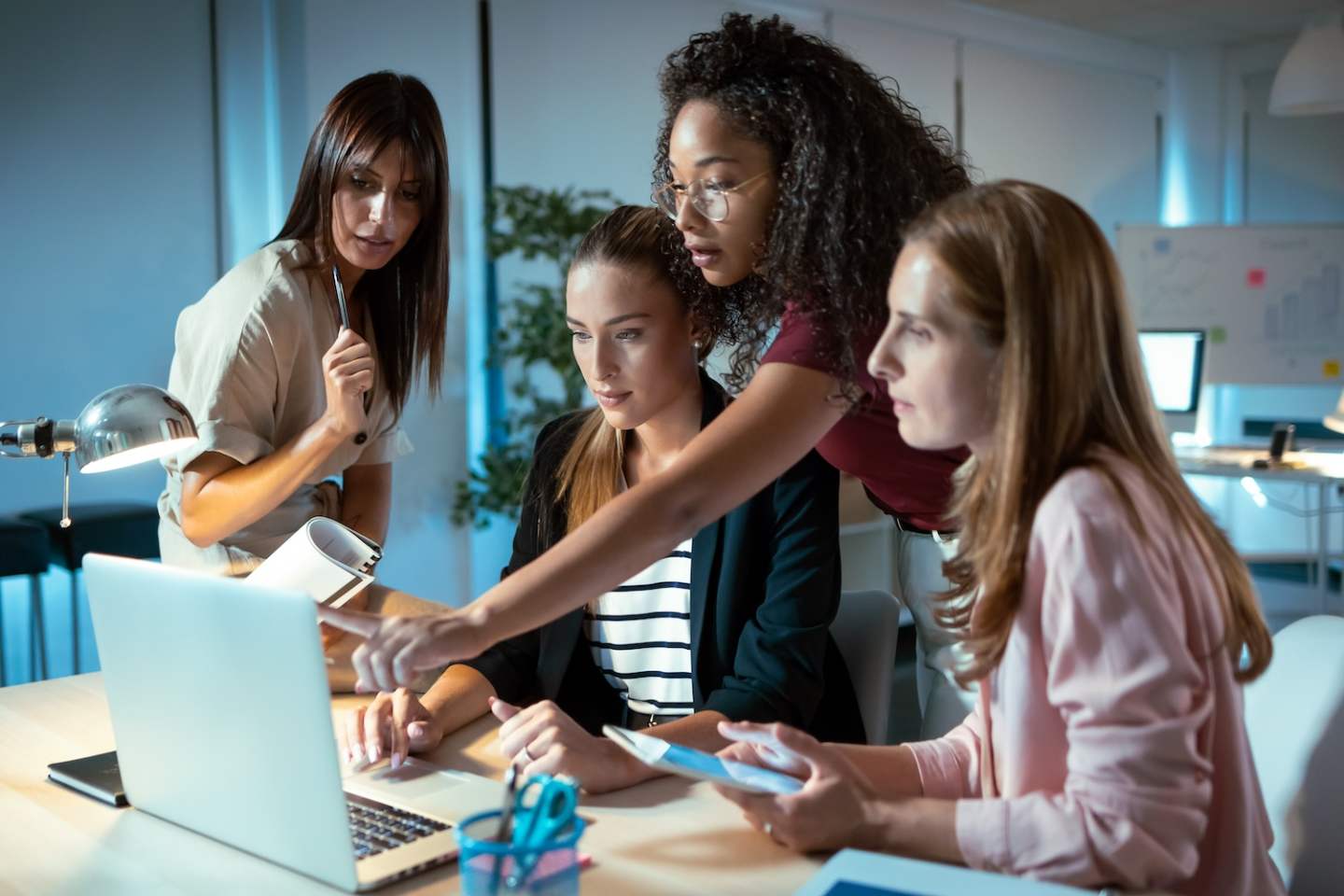 Shot of four smart businesswomen talking and reviewing the latest work done on the computer in a joint workspace.