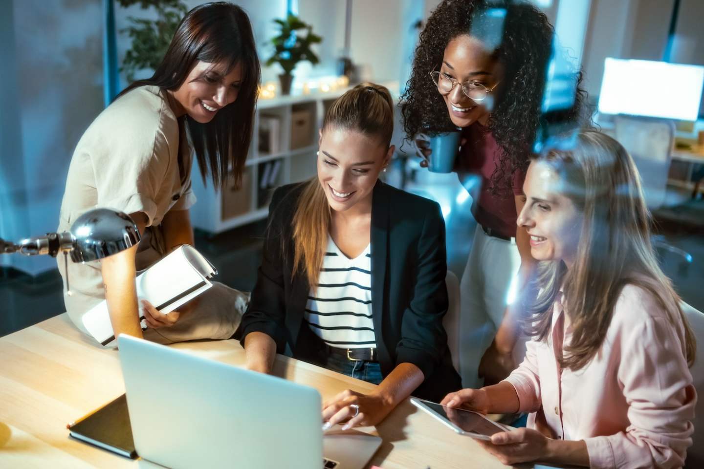 Shot of four smart businesswomen talking and reviewing the latest work done on the computer in a joint workspace.