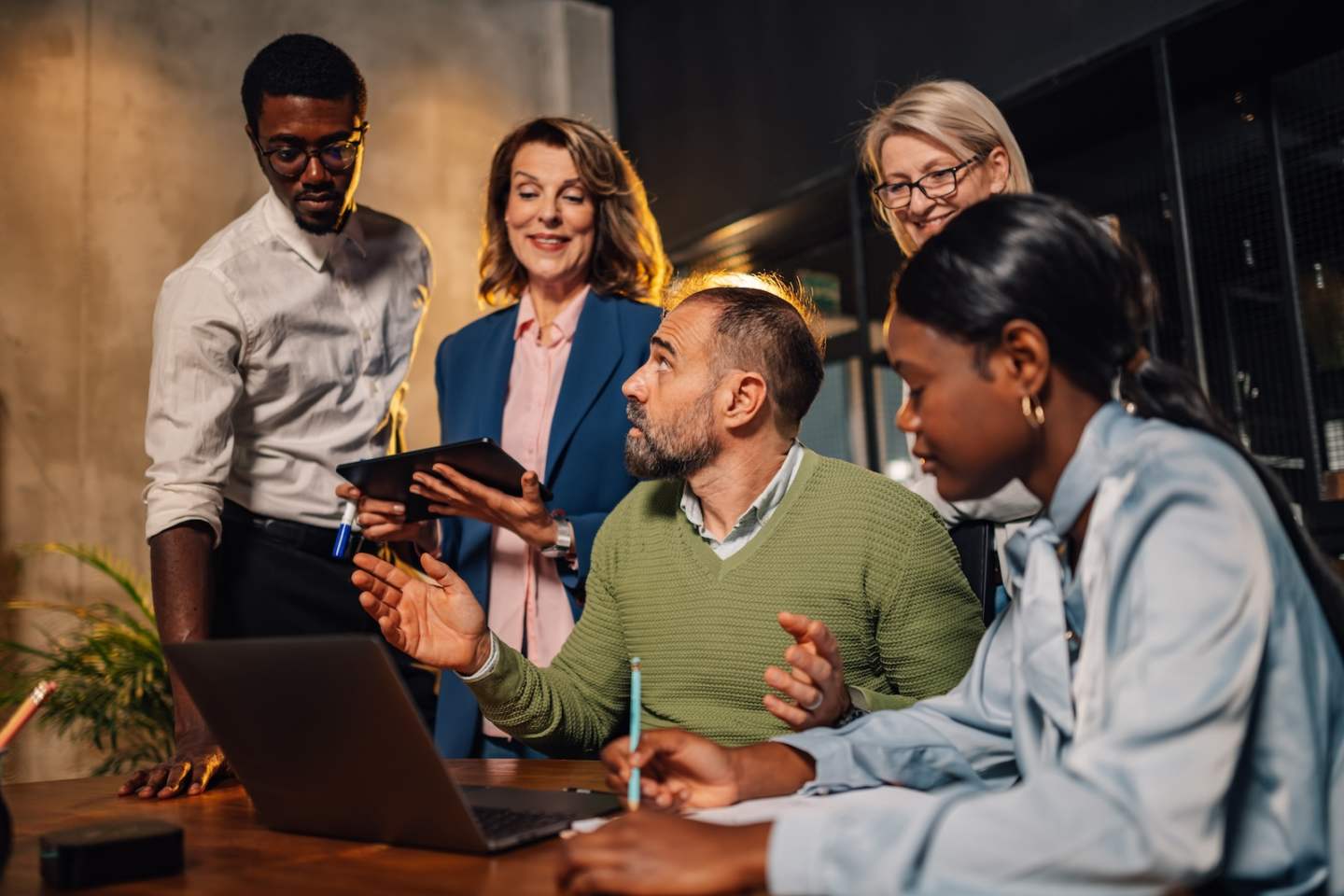 Multiracial team of experts working together on a laptop at modern conference room at corporate company. Diverse businesspeople discussing and collaborating on project during the briefing at boardroom
