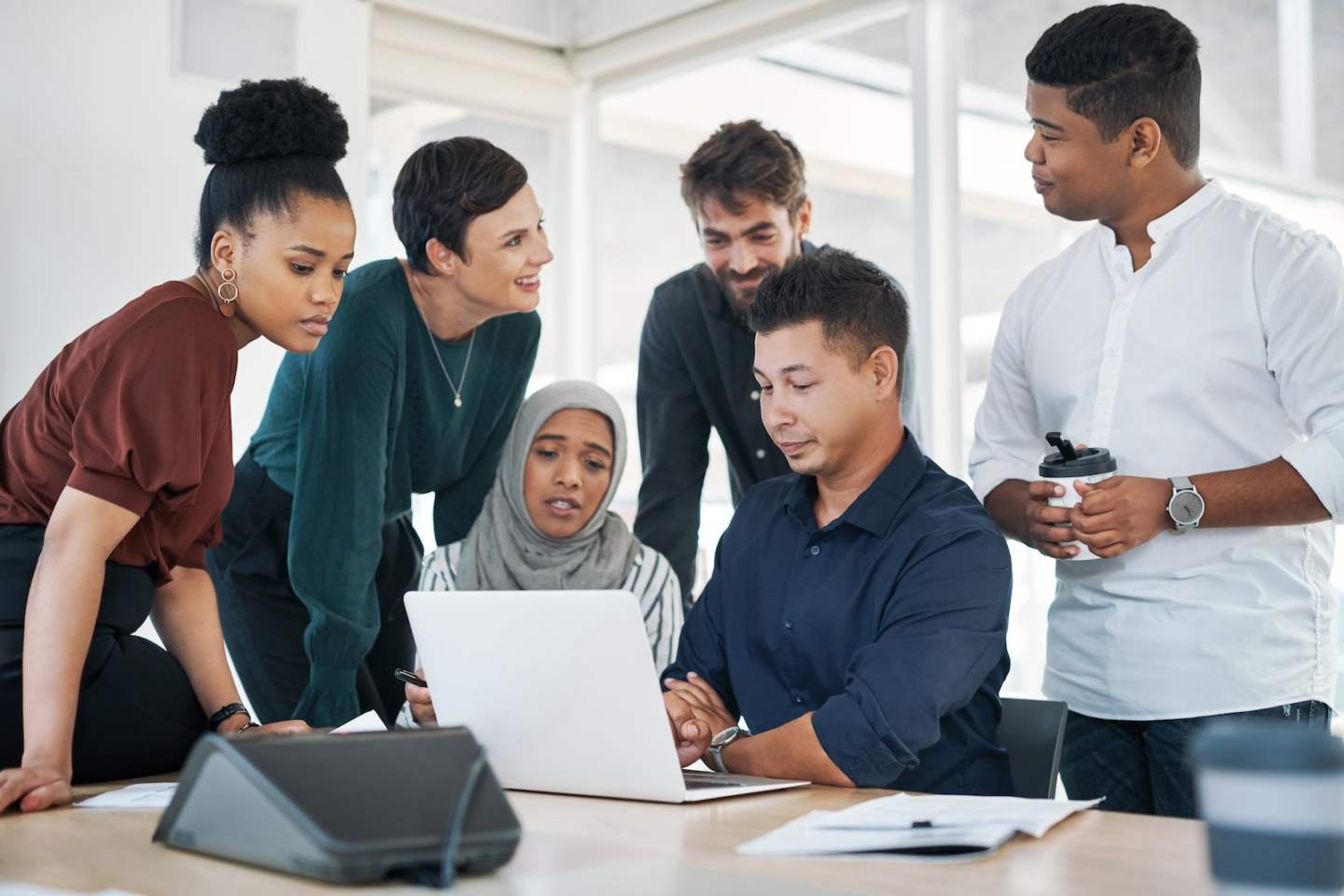 Shot of a group of businesspeople using a laptop during a meeting in a modern office.