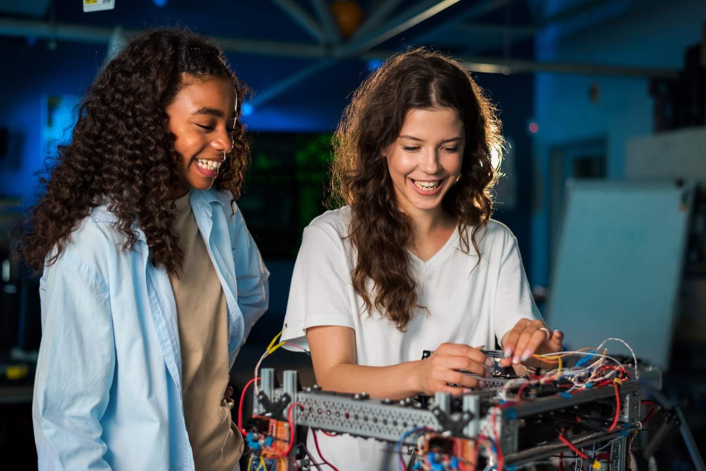 Two young women doing experiments in robotics in a laboratory. Robot on the table