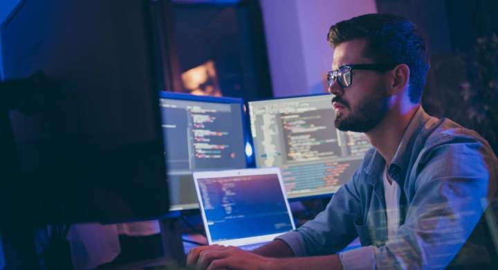 Man working on multiple monitors using AI