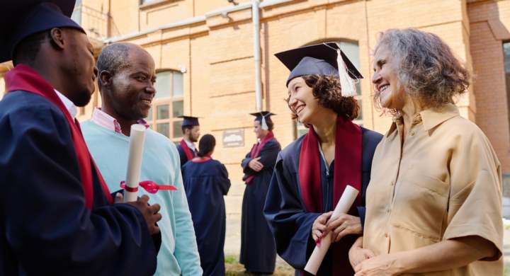 Parents congratulating their children with graduation of university while they standing outdoors