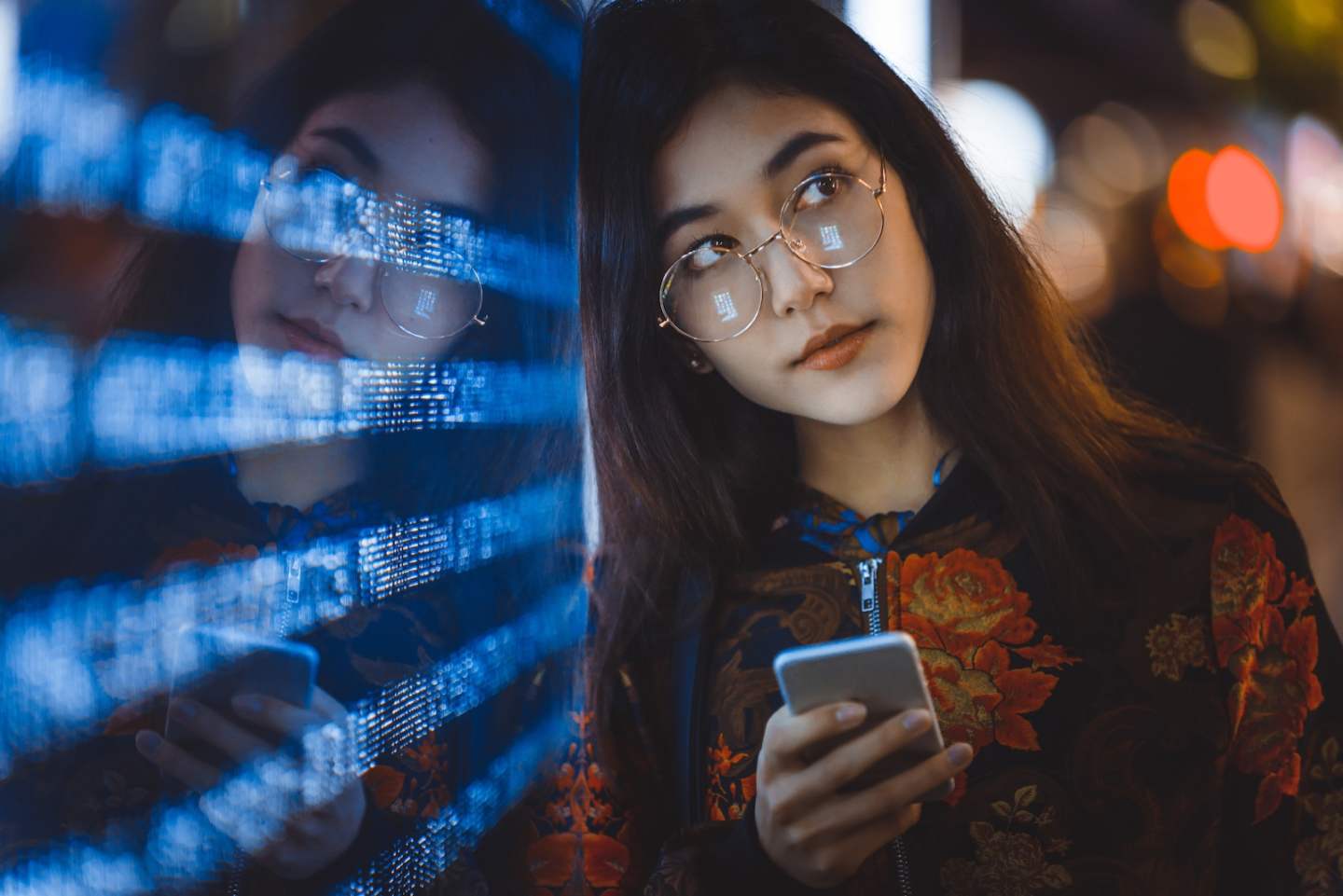 Beautiful mixed race woman posing outdoors, background with blurred neon lights