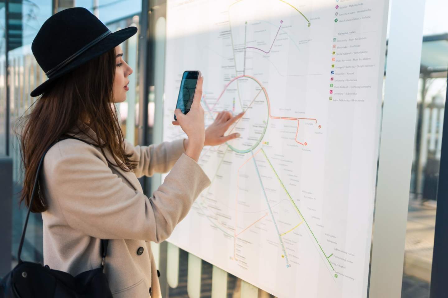 Traveler woman at bus stop takes photo of map public transport routes