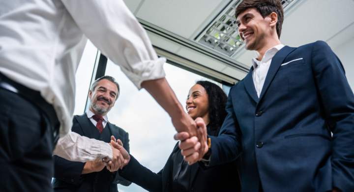Caucasian businessman making a handshake together while stand in office. Attractive team of employee worker enjoy partnership agreement after negotiations for business deal during working in corporate