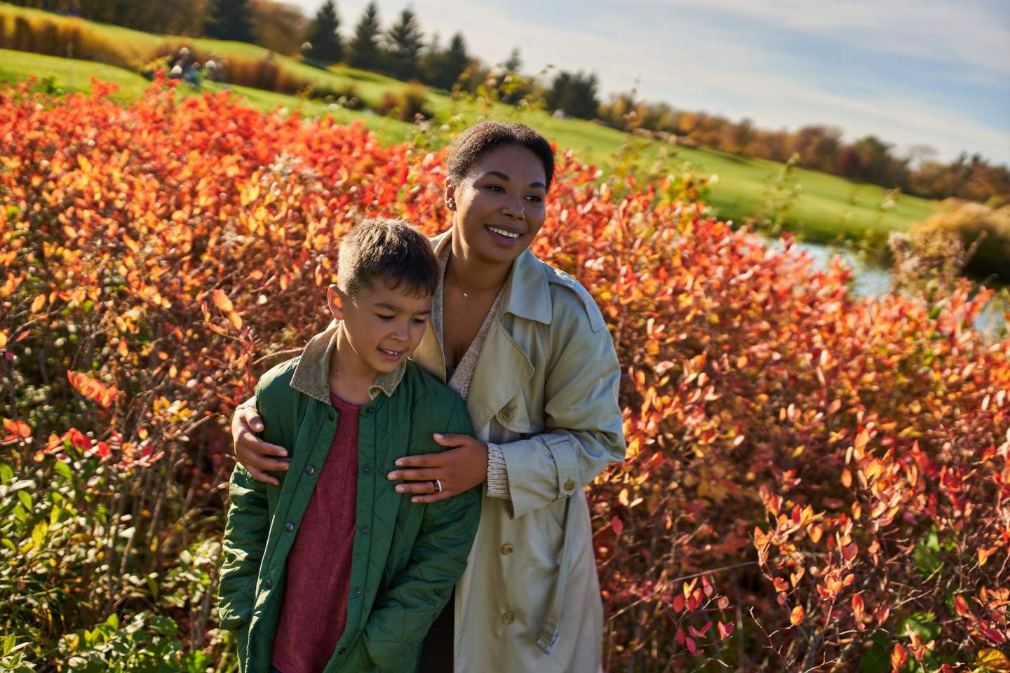 cheerful african american mother in autumnal clothes embracing son, fall season, golden leaves