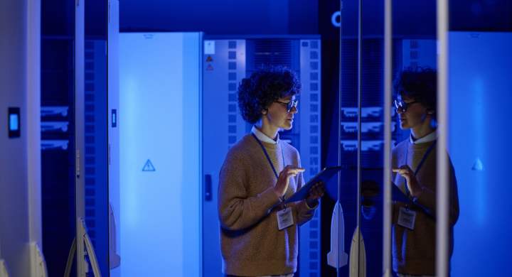 IT specialist working on digital tablet online checking the work of computer system in server room