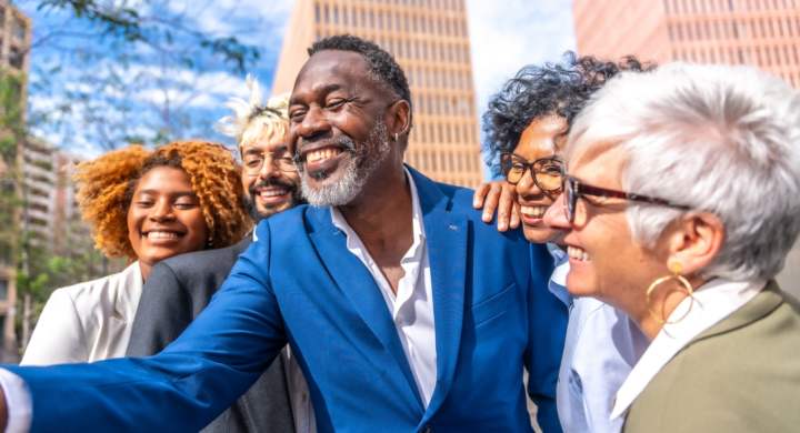 Side view of mature african businessman taking a selfie with colleagues outdoors