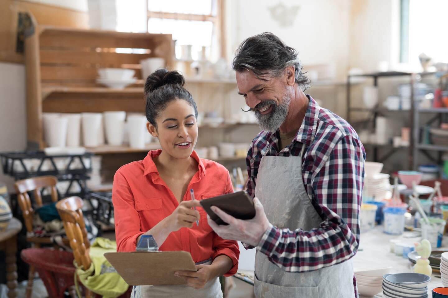 Male and female potter discussing over tablet pc in the pottery workshop
