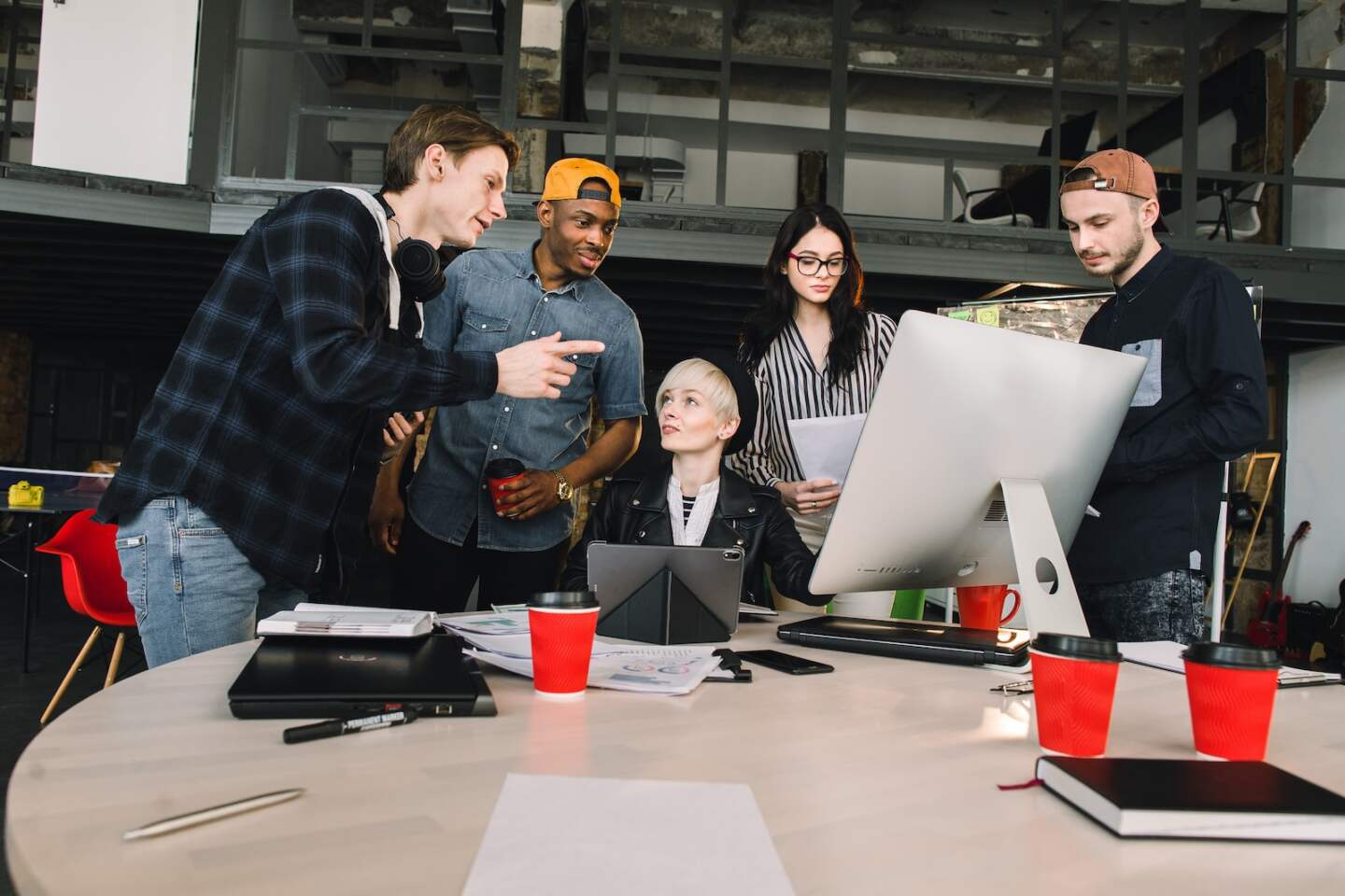 Young six people working in positive environment in loft office, woman sitting at the table and using computer.