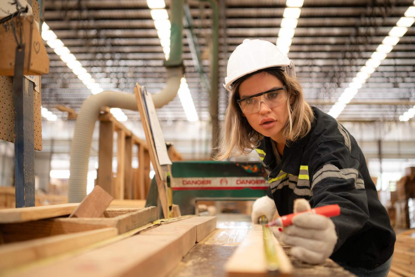 Portrait of young female carpenter working with wood cutter machine in the wooden factory