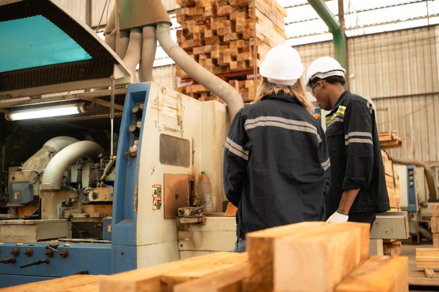 Both workers work in a woodworking factory, Working with wood sawing and cutting machines to produce wooden sheets for making pallets